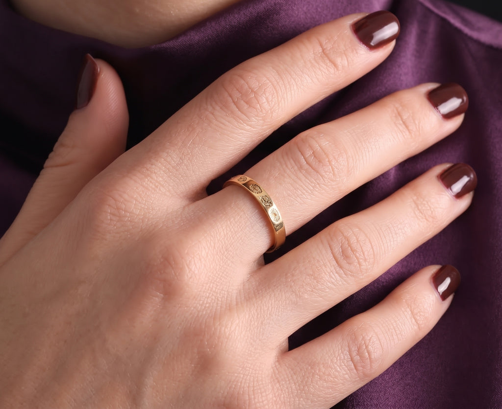Birth flower ring worn, hand resting on purple fabric