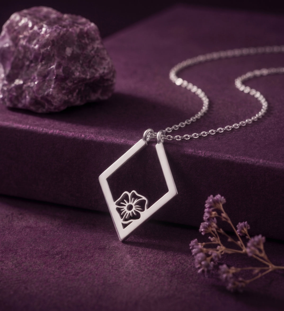 Birth flower ring holder necklace in a silver tone on a plum box
