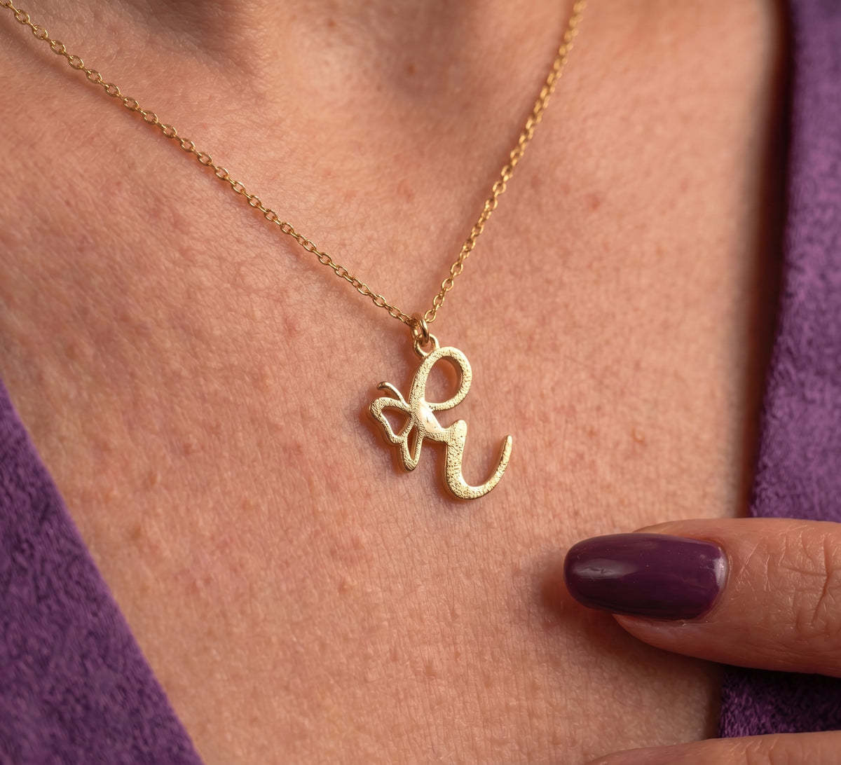 Close-up of the butterfly initial pendant worn on the chest