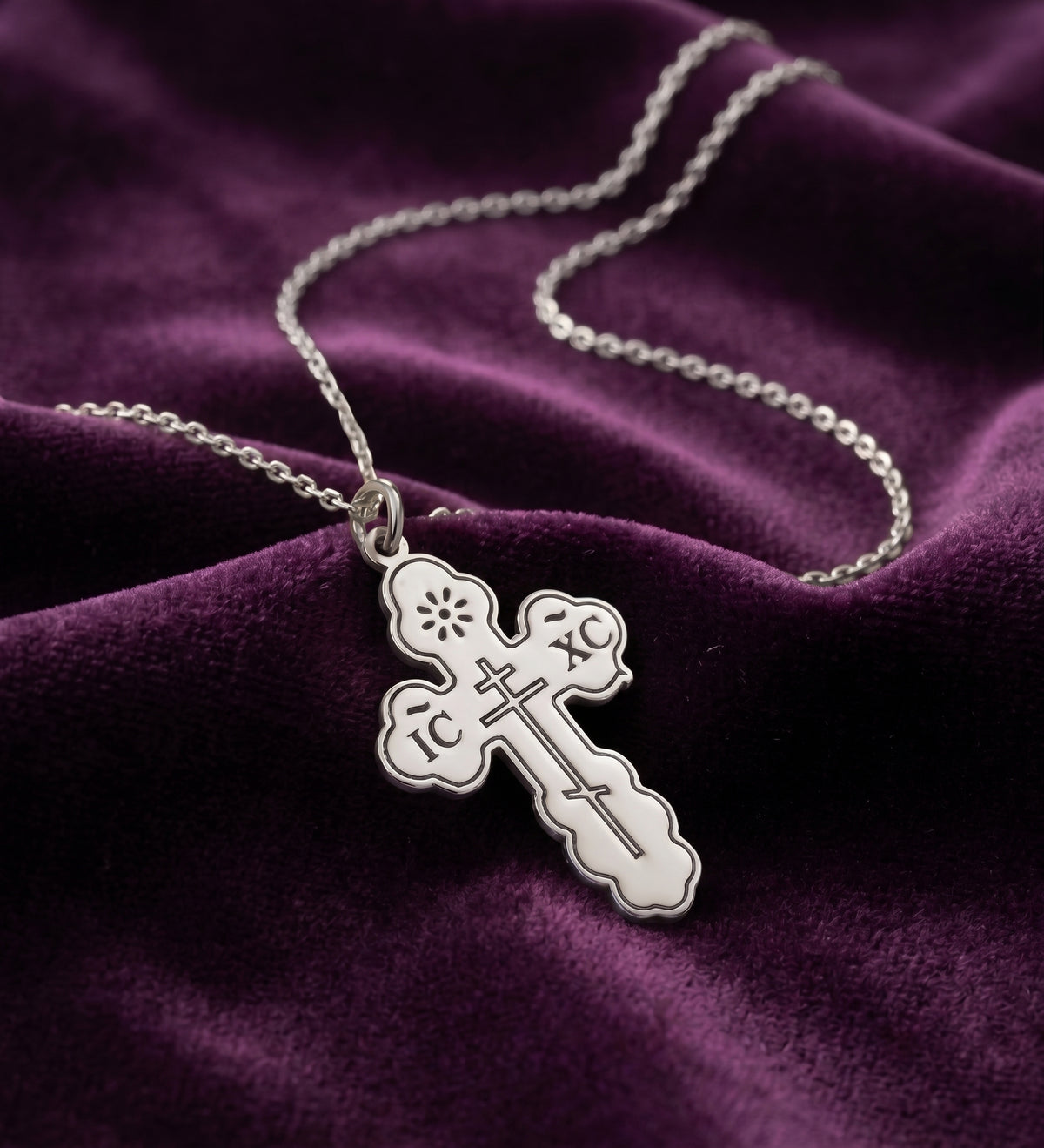 Silver tone engraved cross necklace on purple velvet