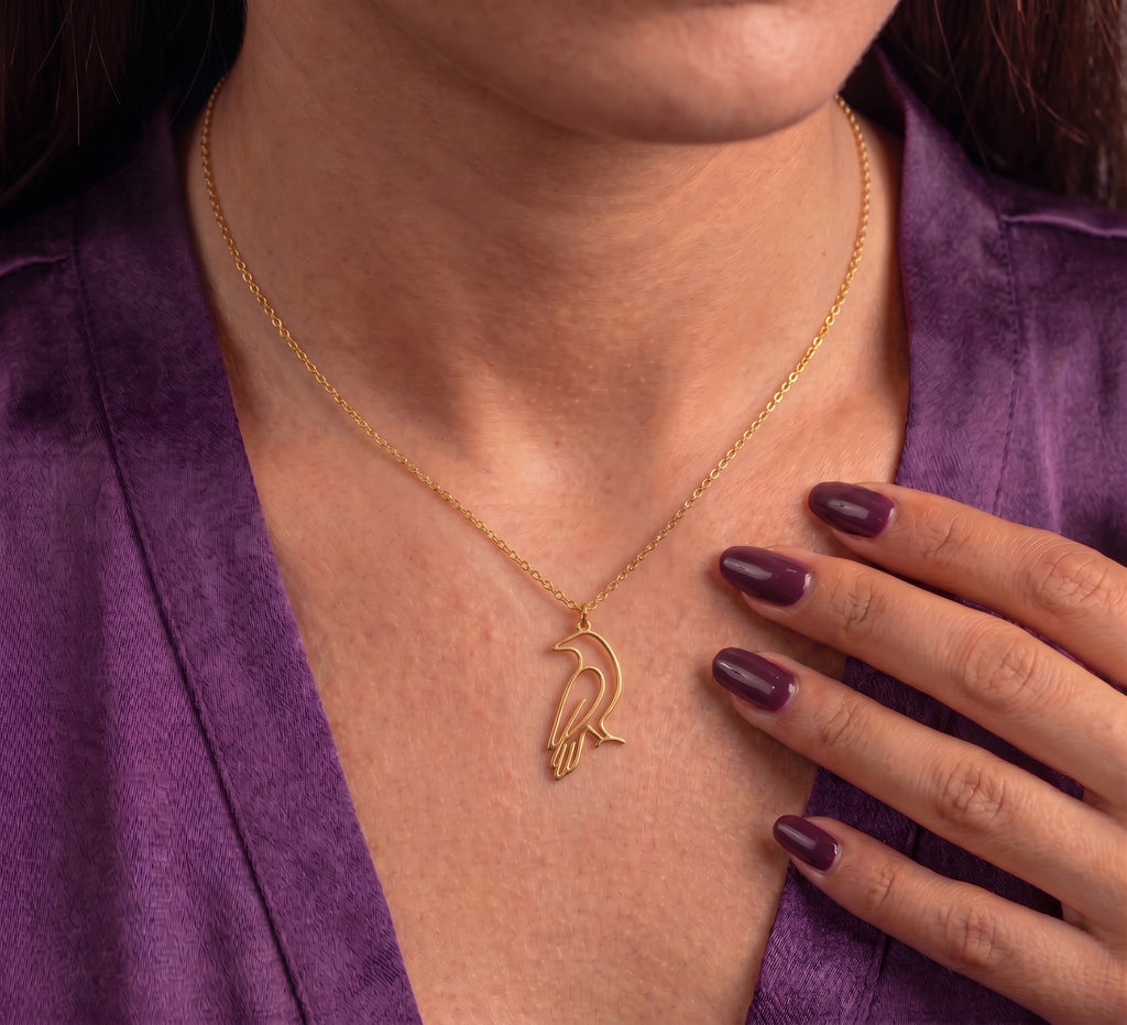 Crow necklace worn, hand resting beside the pendant