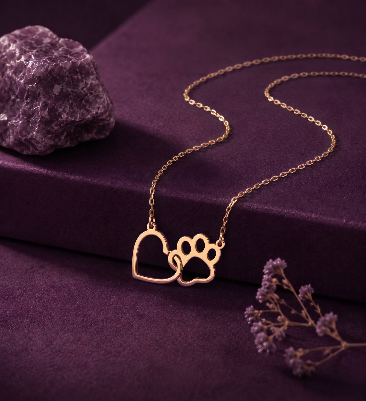 Heart and paw print necklace on a plum box beside an amethyst stone