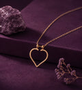Open heart ring holder necklace on a plum box beside an amethyst stone