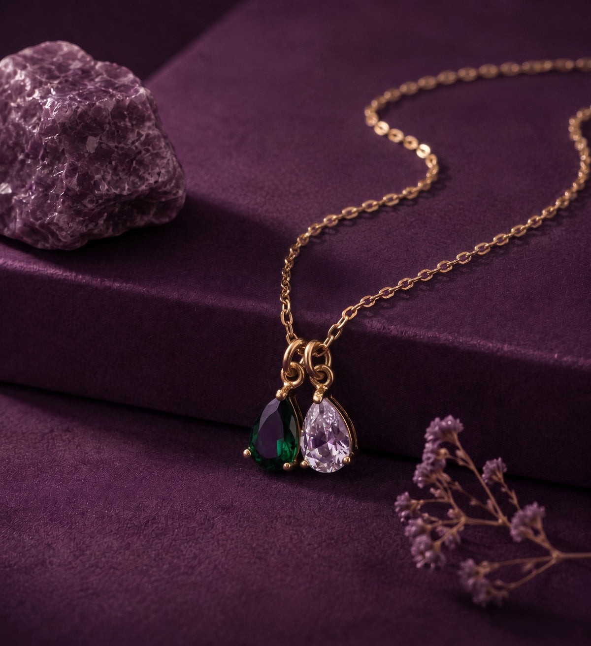 Necklace with a green and a clear pear-shaped stone on a plum box