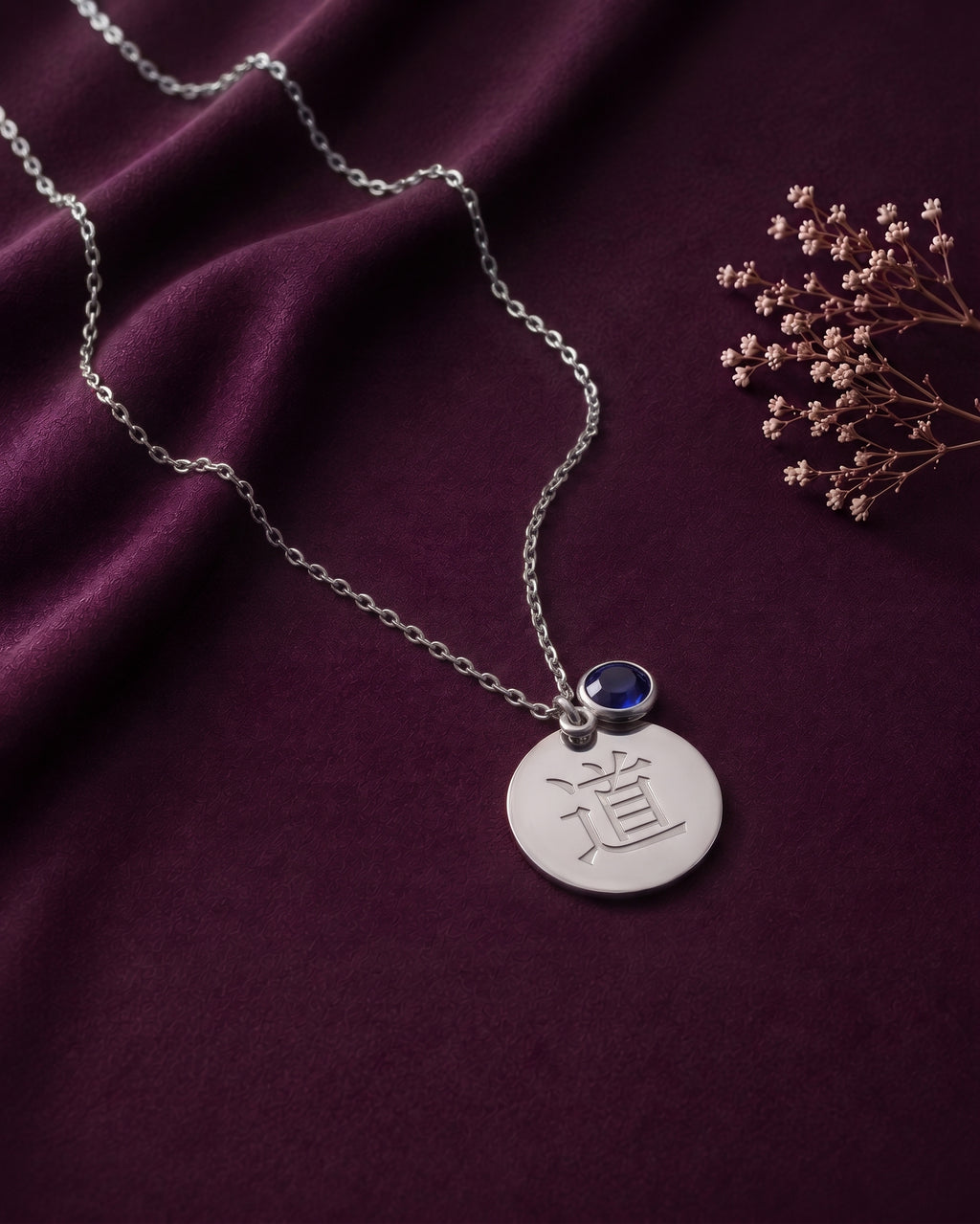 Silver tone kanji disc necklace with a blue stone on purple satin