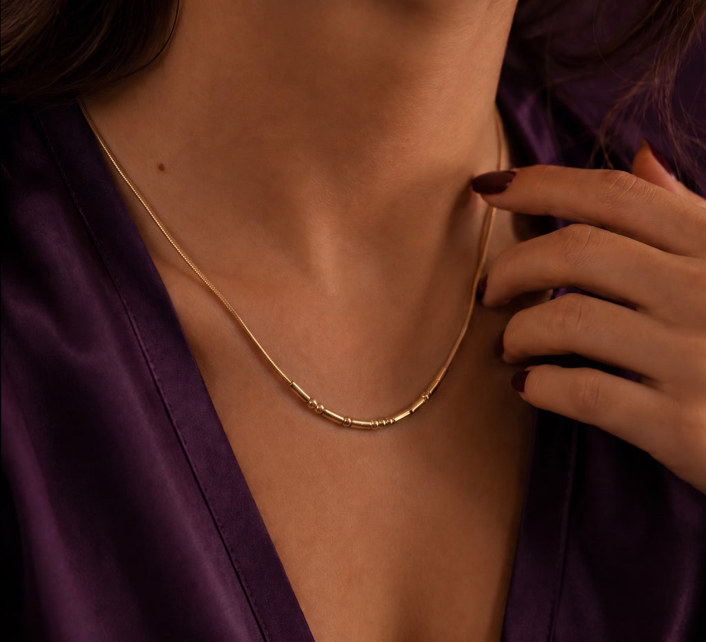 Morse code necklace worn, with a hand resting at the neck