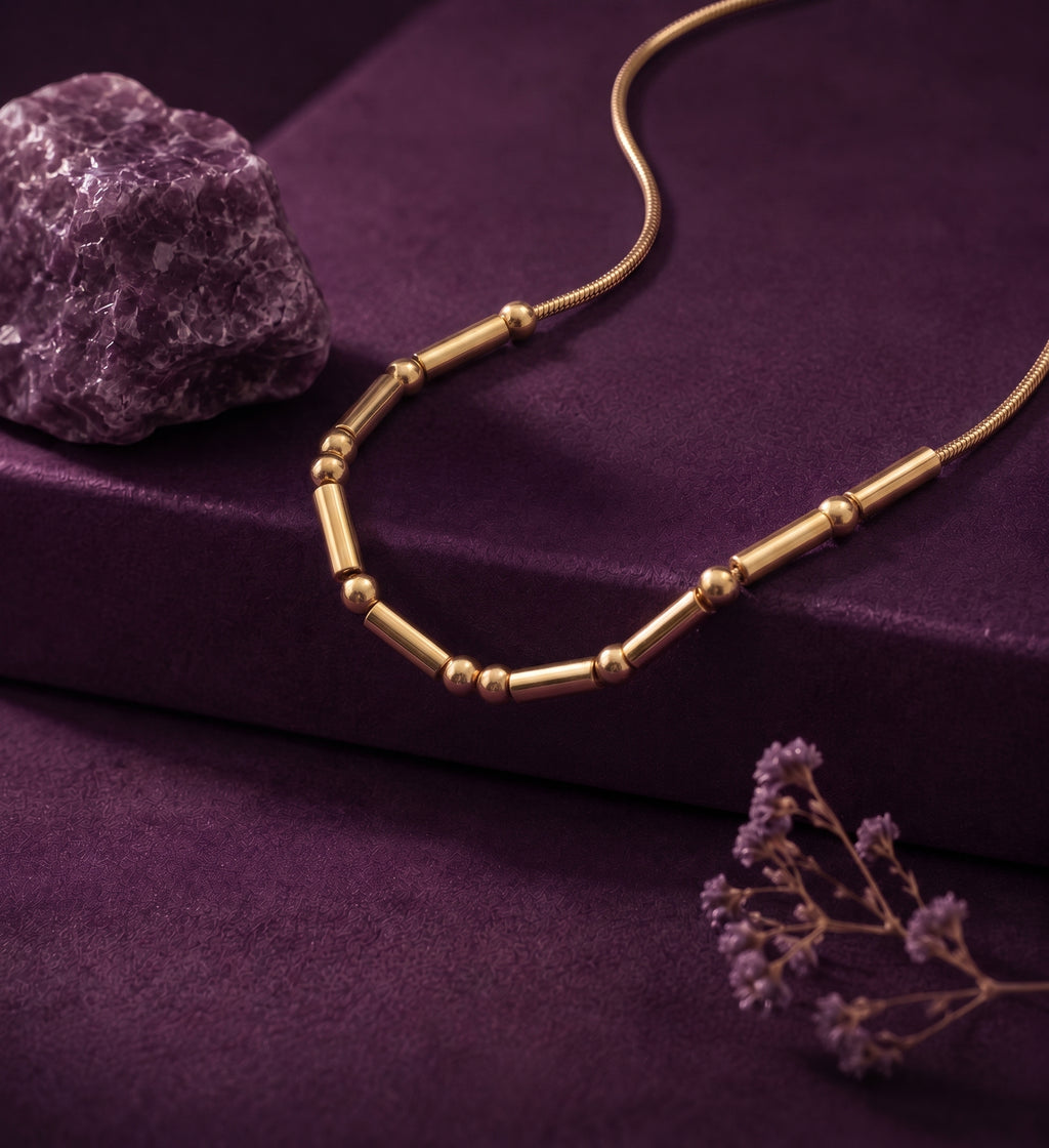 Morse code necklace with beads and bars on purple velvet beside an amethyst stone