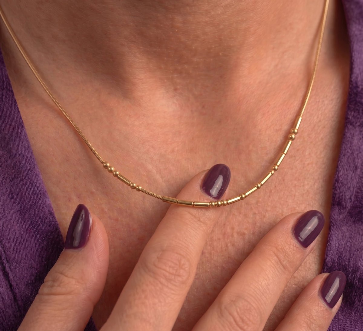 Close-up of the Morse code necklace worn, with a finger touching the chain